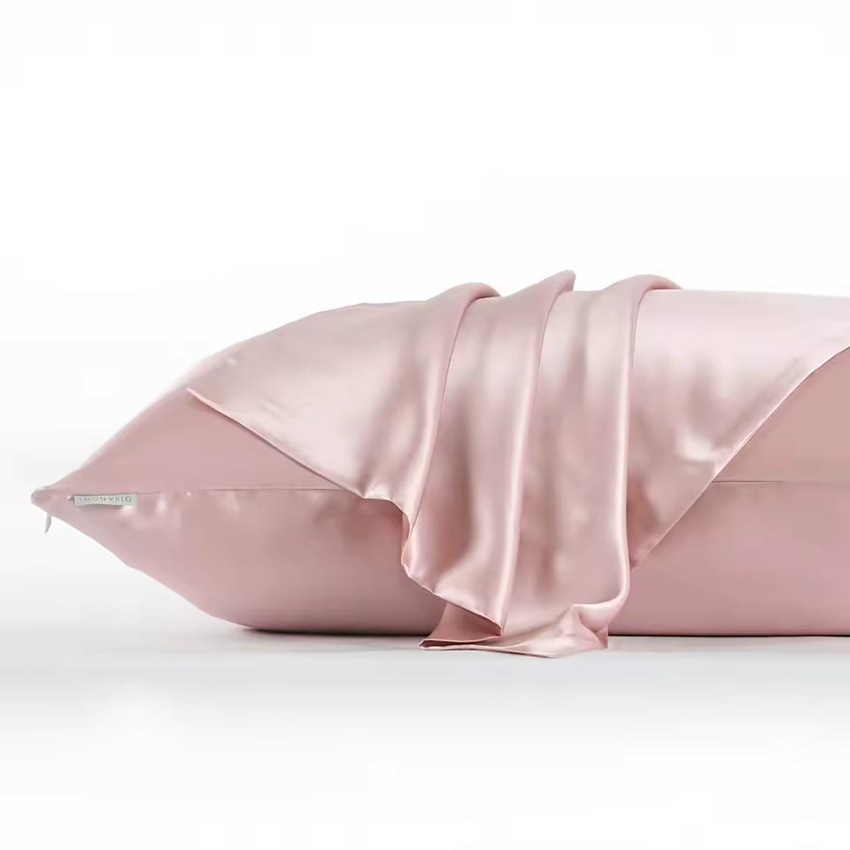 A dusty pink satin pillowcase with a matching satin pillow sham draped over it, set against a clean white background.