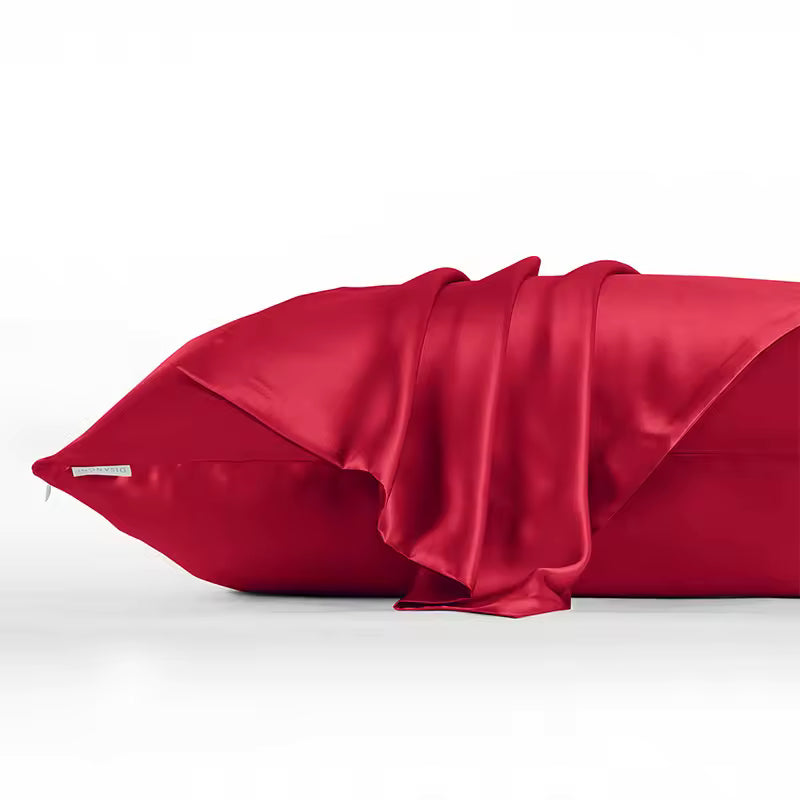 A close-up of a deep red satin pillowcase with a matching satin throw blanket draped over the side, set against a clean white background.